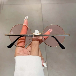 Gros plan de lunettes de soleil rondes vintage avec monture dorée et verres roses clairs
