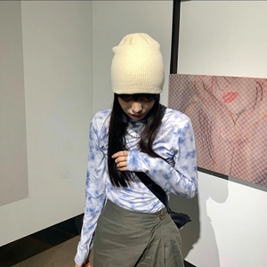 Detailed close-up of the tie-dye knitted sweater texture and winter beanie outfit