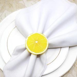 Close-up of a vibrant yellow lemon slice napkin ring on a white plate and tablecloth