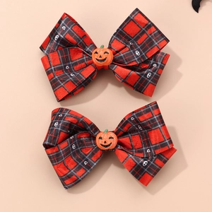 Detailed view of two handmade Halloween pumpkin and skull pattern hair bows for girls