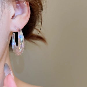 Macro shot of iridescent acrylic hoop earring worn by a model with holographic shine