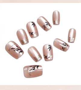 Macro detail of nude pink cat eye press on nails with gold leaf patterns and glitter