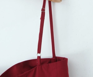 Détail de la bretelle rouge avec boucle métallique réglable et texture du tissu