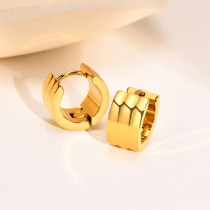 Detailed view of chunky gold hoop earrings with a triple-layered textured stripe design