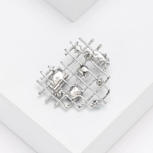Detail of silver heart brooch with sparkling rhinestones and white pearls on a pedestal