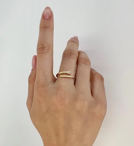 Macro detail of gold snake-style wrap ring with cubic zirconia on a white background
