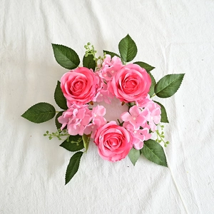 Close-up of artificial pink rose candle ring with green leaves for festive decoration