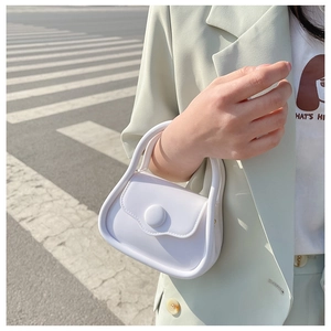 Mini white macaron chain bag held by model in street scene with a minimalist style