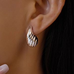 Gros plan d'une boucle d'oreille argentée texturée en forme de goutte portée par un mannequin