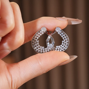 Detailed view of silver teardrop hoop earrings with crystal pavé held by hand