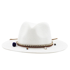 Détail d'un chapeau de paille blanc avec pompons, coquillages et perles décoratives