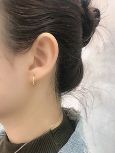 Close-up of minimalist gold S925 sterling silver hoop earrings worn on a model ear