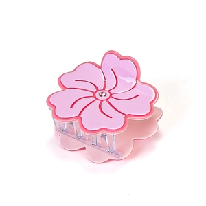 Pink floral acetate hair claw clip with crystal center and transparent base on white background