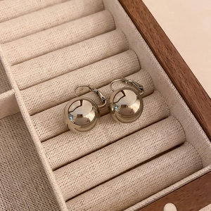 Vue rapprochée de boucles d'oreilles sphériques argentées polies dans un écrin en bois