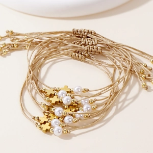 Detail of bohemian braided rope bracelets with gold cross and white pearls