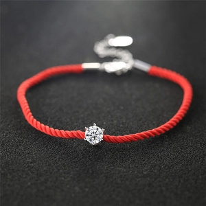 Detailed macro view of a red woven rope bracelet featuring a single round-cut diamond setting