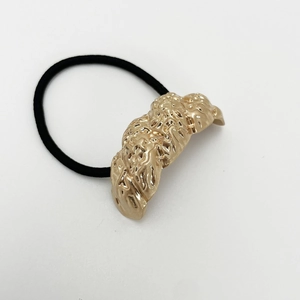 Detail of black elastic hair tie featuring an irregular textured gold alloy ornament