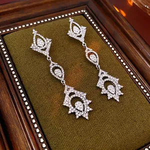 Luxurious silver long drop earrings with white rhinestones on green velvet