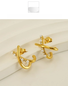 Detail of gold X-shaped earrings with pearls and rhinestones on a display stand