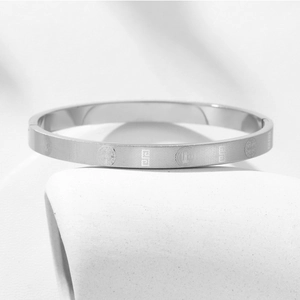 Macro detail of silver stainless steel bangle with engraved religious cross emblems