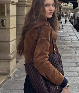 Outdoor street style view of a dark brown suede jacket and a woven oversized handbag