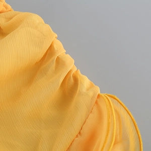 Vue détaillée du tissu en mousseline jaune avec une texture plissée verticale raffinée