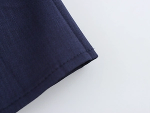 Dettaglio del tessuto intrecciato blu navy con cuciture precise sull'orlo dell'abito