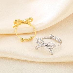 Minimalist adjustable bow ring set in gold and silver finish on satin background