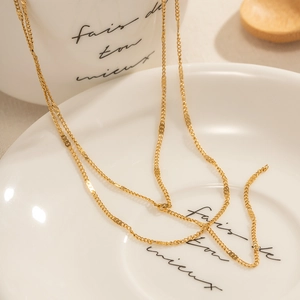 Minimalist double-layered 18K gold stainless steel Y-necklace on white ceramic tray