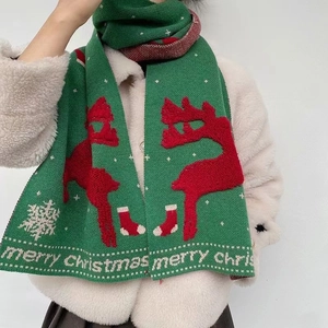 Detail of green knitted Christmas scarf featuring red reindeer and white snowflakes