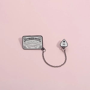 Black and white enamel brooch with psychic circle design connected by a metal chain