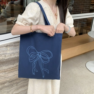 Bolso tote de lona azul marino con estampado de lazo mostrado en entorno exterior