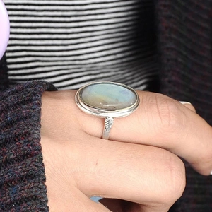 Macro detail of the silver ring band featuring intricate leaf engravings and the oval stone