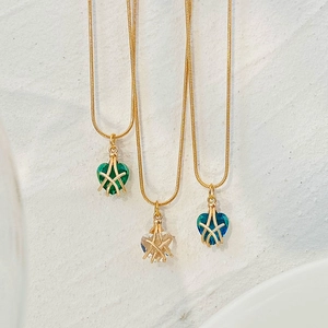 Detalle de los colgantes de corazón y estrella en verde, azul y claro sobre cadenas de oro