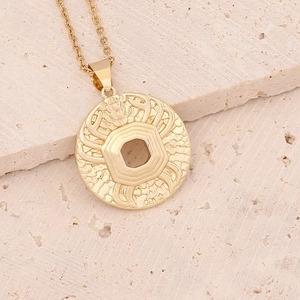 Macro detail of golden 18K gold zodiac pendant with hollow hex pattern on beige stone