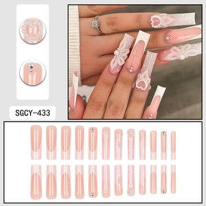 Faux ongles French extra-longs avec base gelée rose, pétales 3D et breloques cœur perlé