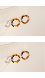 Close-up of golden hoop earrings featuring vibrant rainbow-colored zircon stone inlay