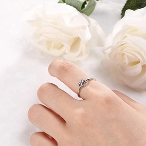 Polished titanium steel knot ring for women with minimalist heart knot design on white roses