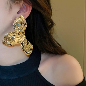 Nahaufnahme großer goldener Blumenohrring mit Hammerschlag-Textur an einem Modell