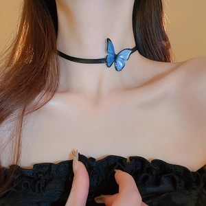 Close-up of a blue butterfly pendant on a black choker necklace worn by a model