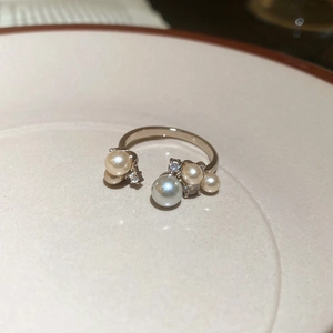 Detail of vintage gold ring with pearls and zircons on a white ceramic tray