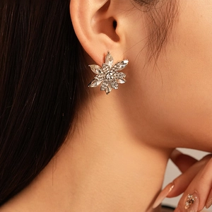 Close-up of sparkling floral stud earrings with crystals on a model's ear