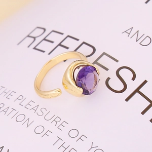 Minimalist gold open ring with a faceted purple round gemstone on a white background