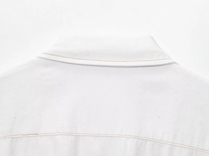 Gros plan détaillé du col du gilet blanc avec surpiqûres orange et texture de denim