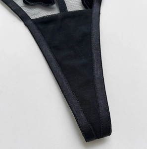 Detail of black mesh and satin thong showing precise V-cut stitching and high-quality fabric