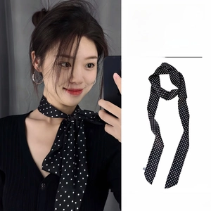 Détail d'un foulard en soie à pois noirs et blancs, noué autour du cou avec un beau drapé
