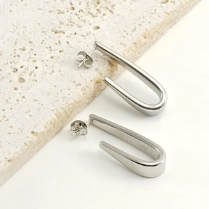 Détail macro de longues boucles d'oreilles en U en acier inoxydable poli et brillant