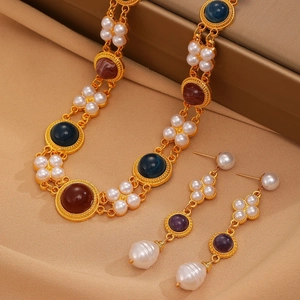 Detail of vintage gold necklace and pearl earrings with colorful gemstones on silk