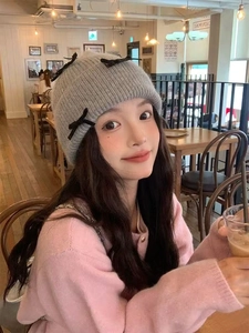 Detailed texture of grey knit hat featuring black velvet bows in a cozy cafe setting
