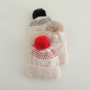 Gros plan de bonnets en tricot pour enfants avec pompons et jolis motifs de cœur